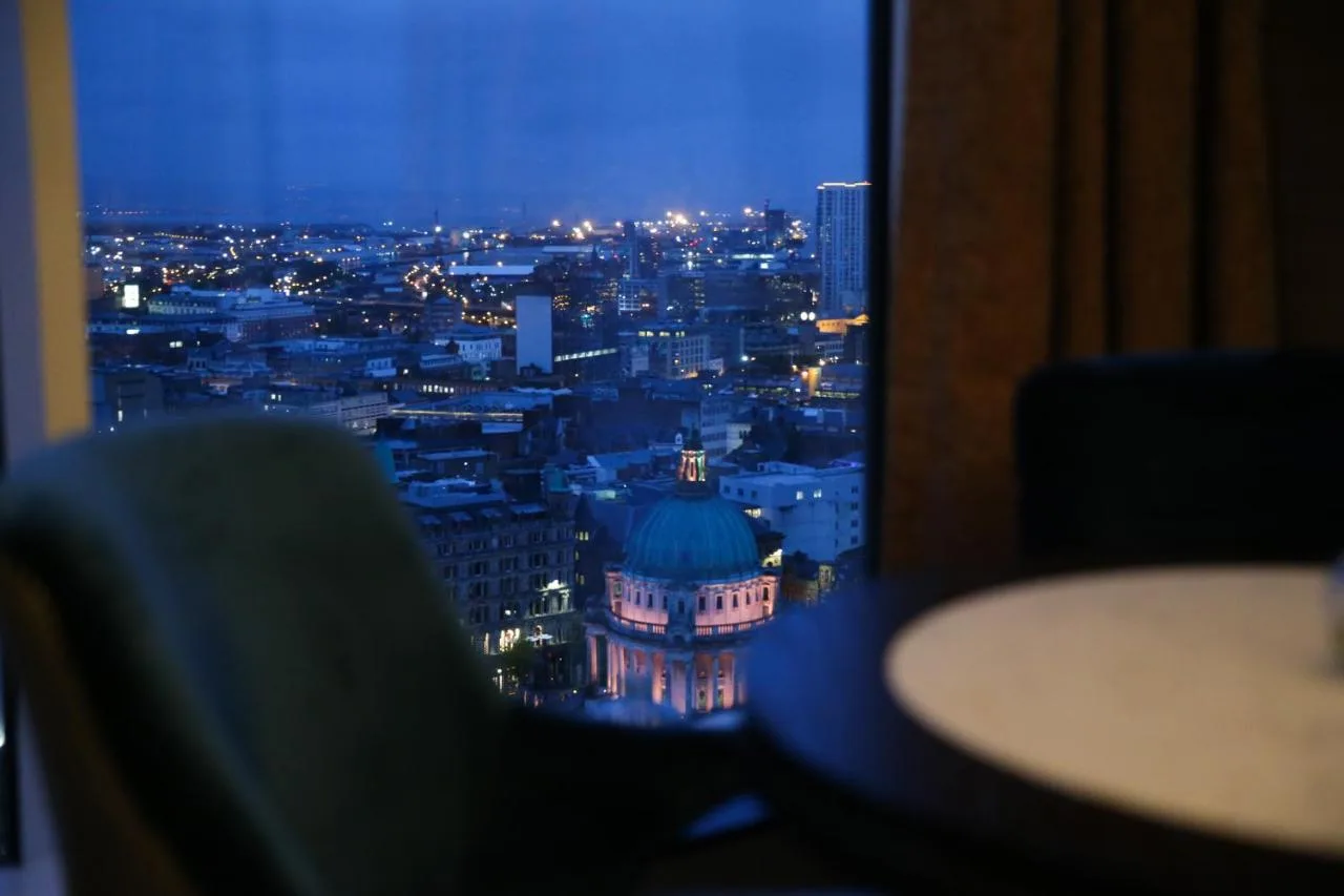a room with a view of a city at night at Grand Central Hotel Belfast in Belfast