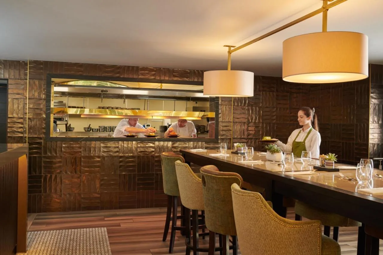 a restaurant with a long bar with people in the kitchen at Grand Central Hotel Belfast in Belfast